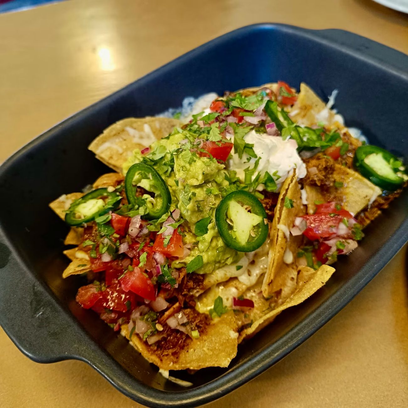 Nachos Alfredo gratinados con guacamole y jalapeños